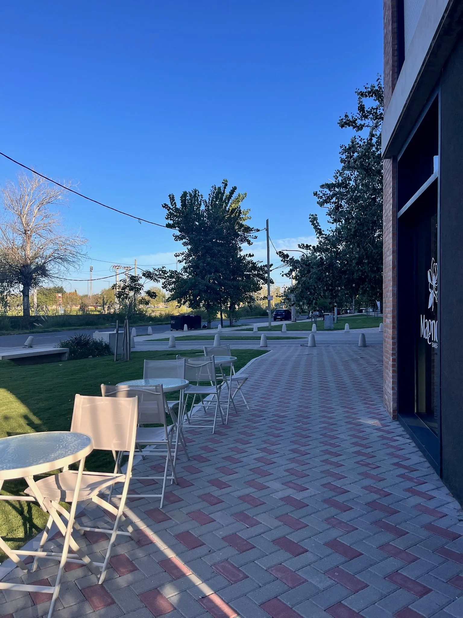 El local visto desde la vereda, con las mesas al aire libre y el cartel de Magnolia